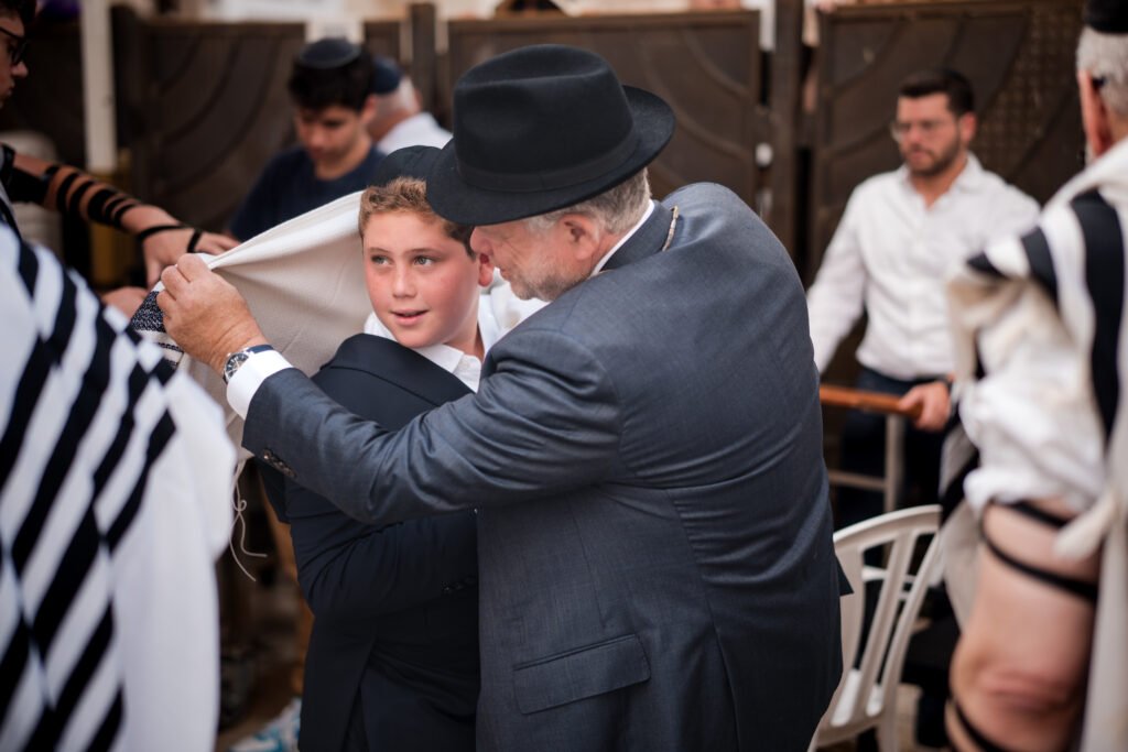 Boy holding a Torah scroll beside a man in a dark suit