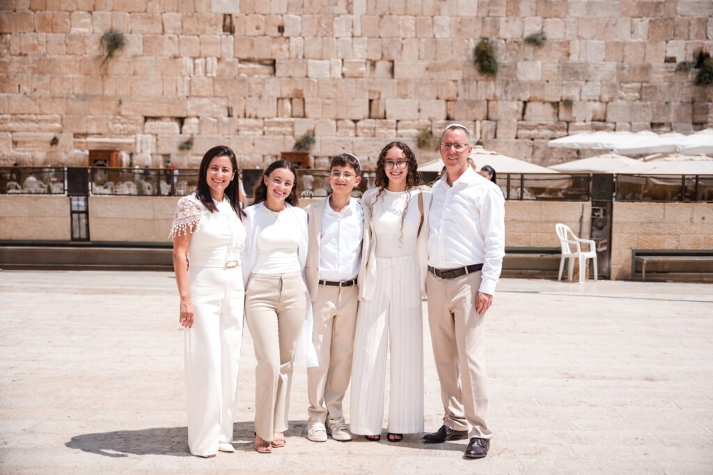 Family in white clothing posing in the Western Wall plaza