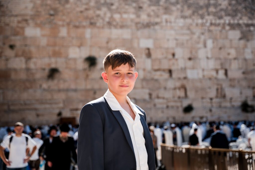 Bar mitzvah boy in a dark jacket overlooking the Western Wall plaza