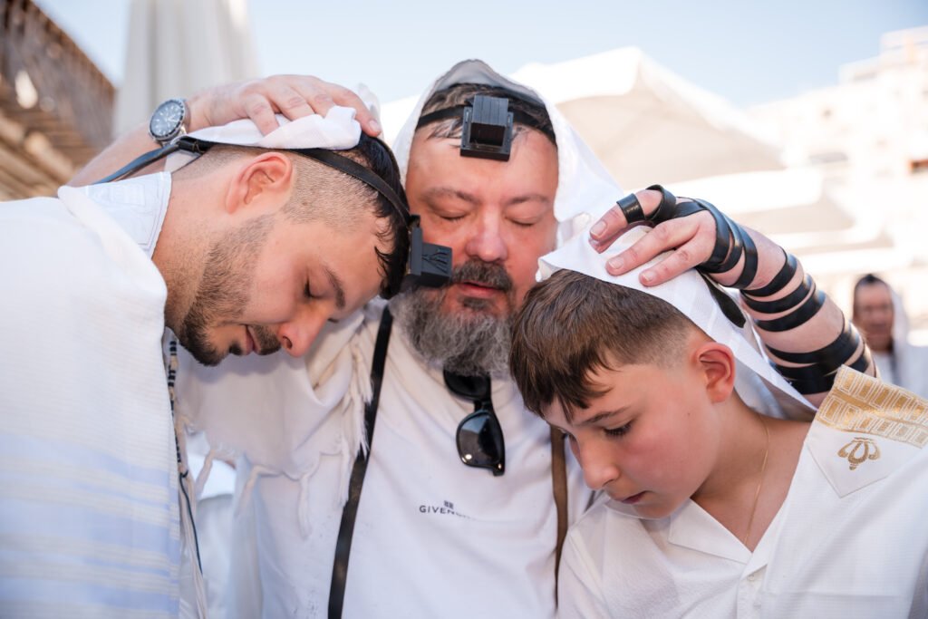 Man placing his hands on two boys during a blessing at the Kotel