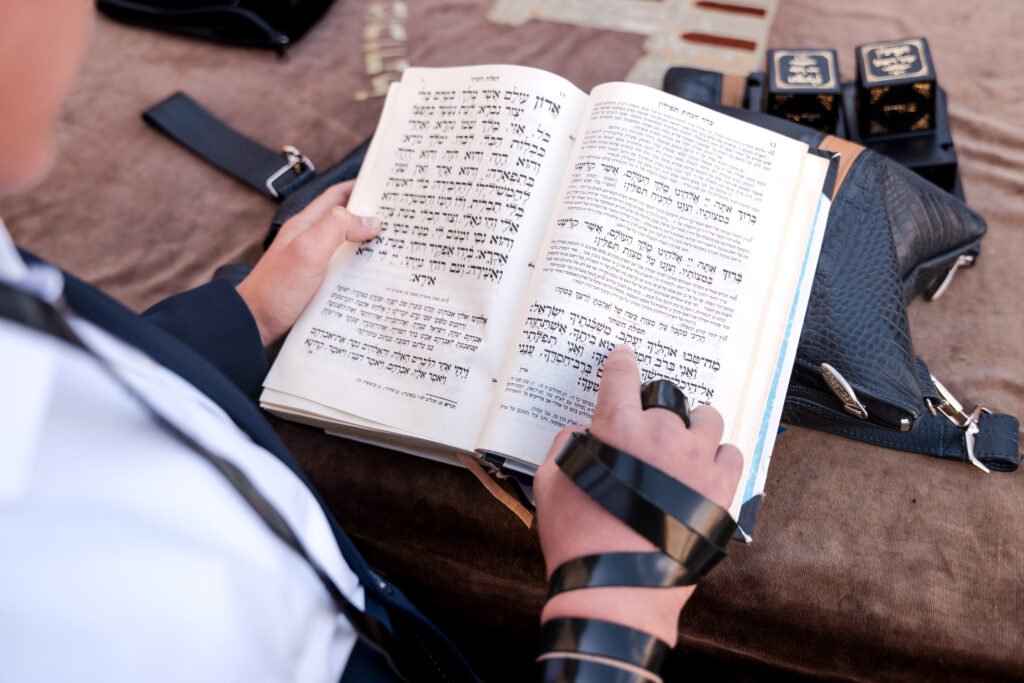 Close-up of a prayer book and an arm wrapped in tefillin
