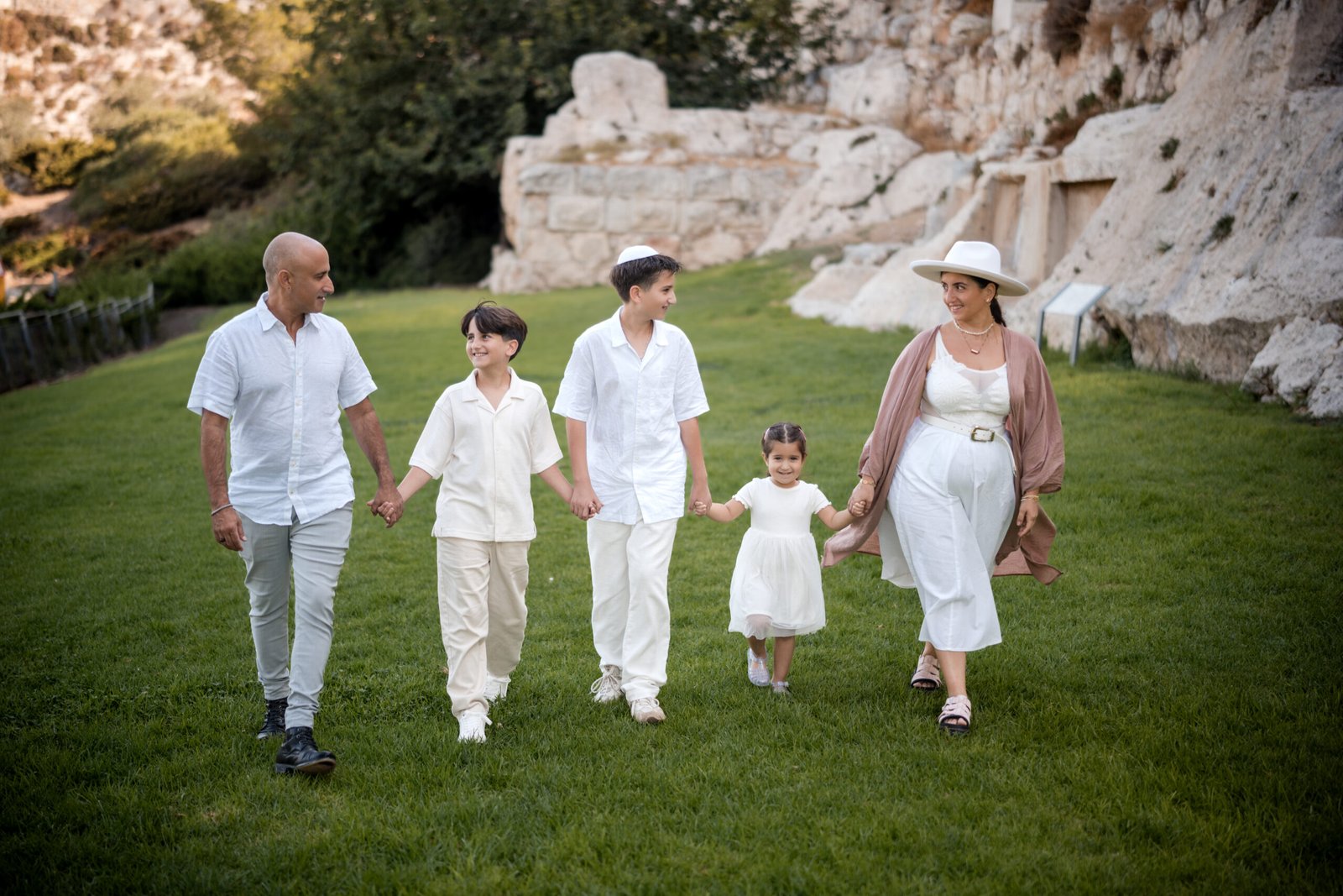 Family walking on the grass at Jaffa Promenade in Jerusalem’s Old City, captured by Pais Photos, professional Bar Mitzvah and family photography.