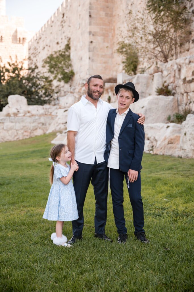 Father holding his young daughter’s hand and looking at her on the grass in Jerusalem’s Old City.