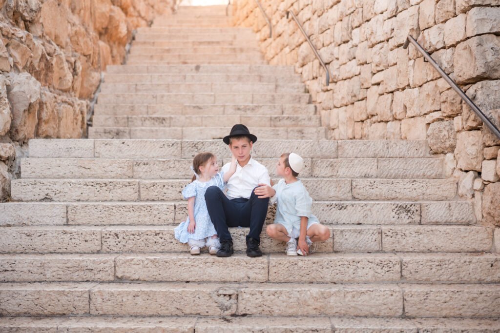 Boy sitting with two young children on stone steps in Jerusalem
