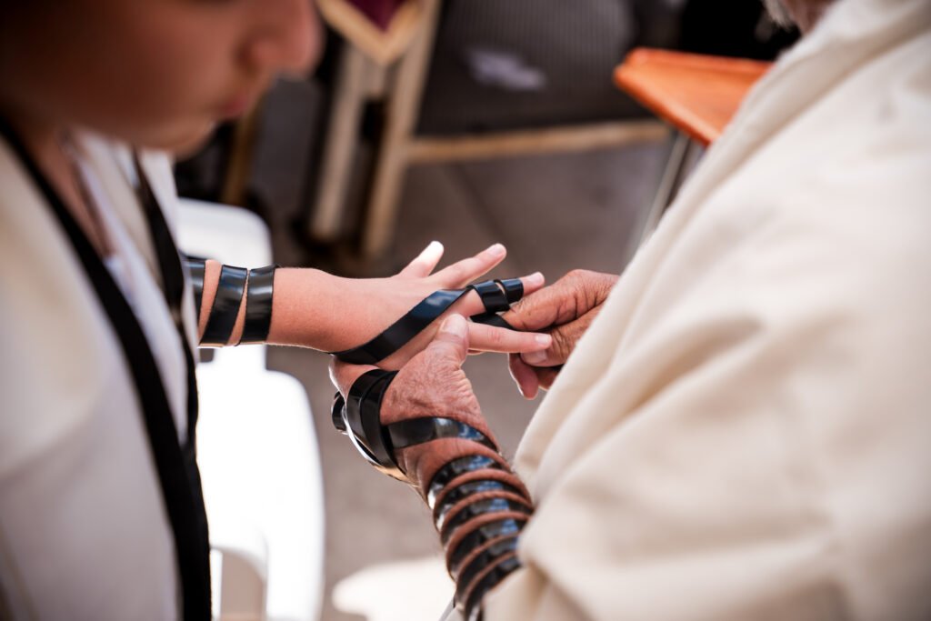 Close-up of hands wrapping tefillin around an arm