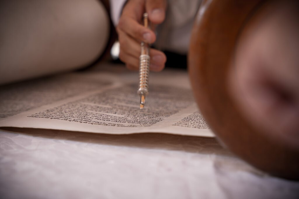 Close-up of a Torah pointer following the text of an open scroll