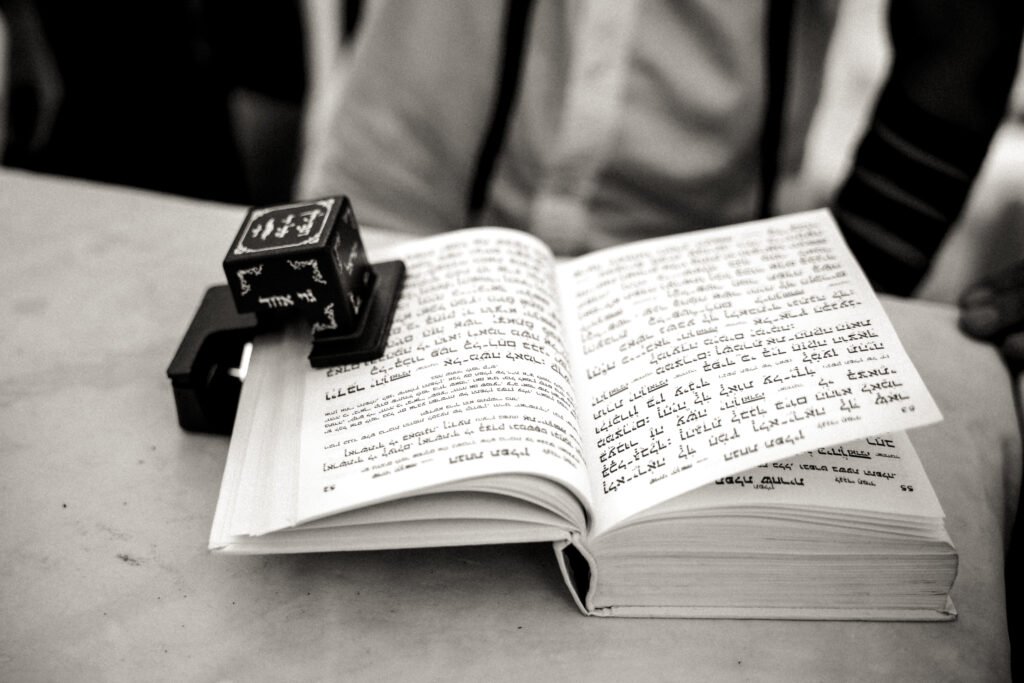 Black and white close-up of tefillin resting on an open prayer book