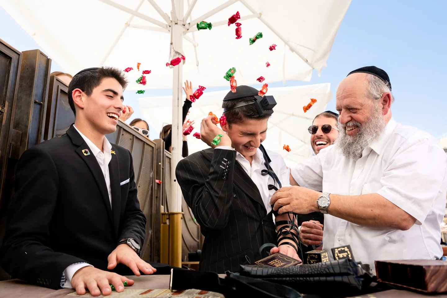 Family members smiling during a Bar Mitzvah ceremony as candies are thrown
